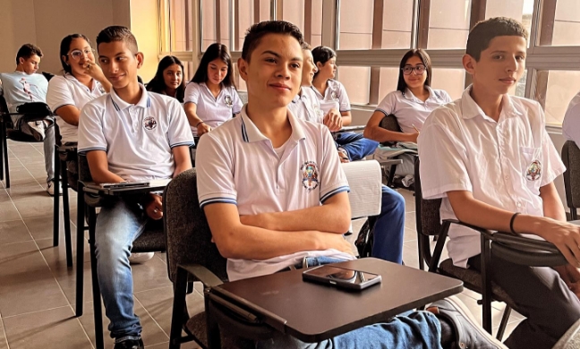 Jóvenes con uniforme escolar sentados en salón de clase