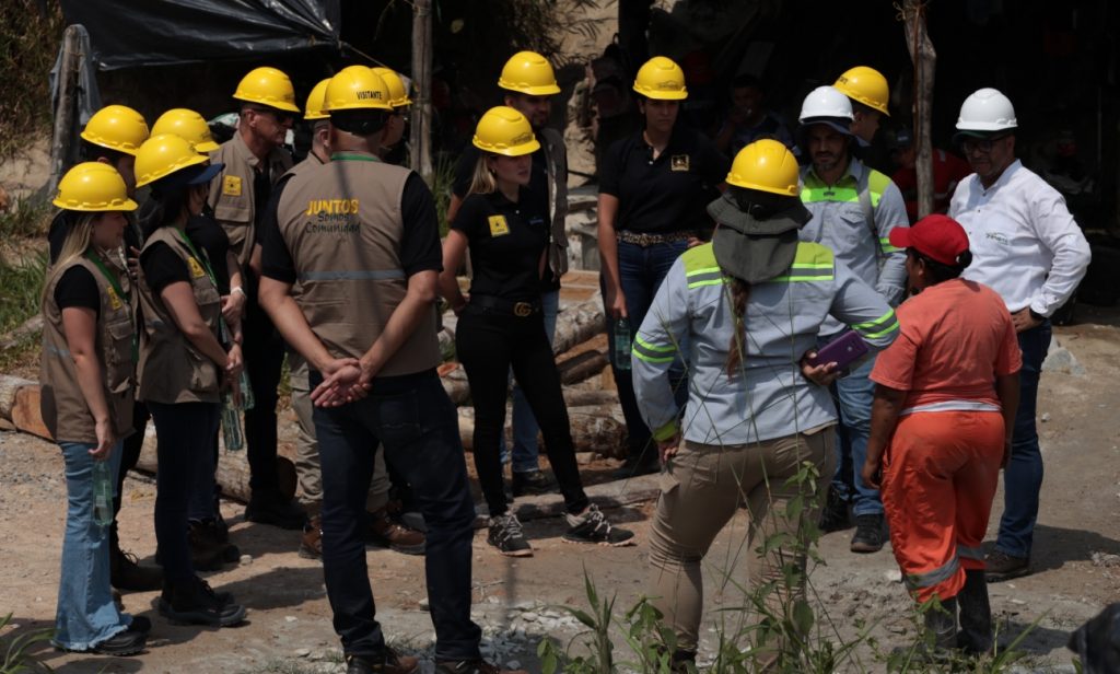 Grupo de hombres y mujeres con cascos amarillos en zona minera
